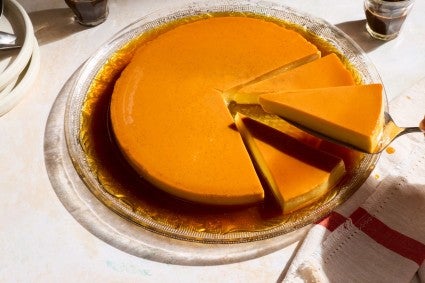 Whole flan with one slice being lifted by a serving utensil